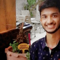 Adil smiling next to a Keep Smiling sign